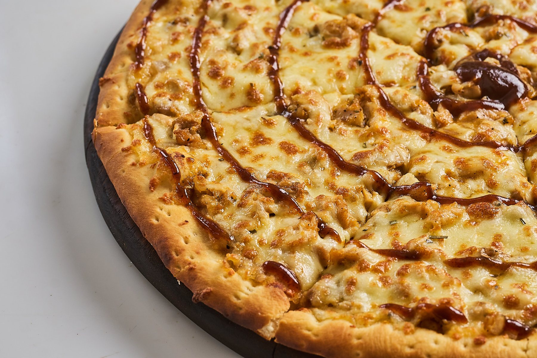 Wood-fired BBQ pizza on a wooden paddle
